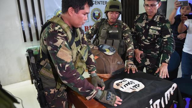 Philippine Army troopers  assisted by military spokesperson in Marawi Lieutenant Colonel Jo-Arr Herrera (R), prepare to display an ISIS flag and 11kg of the illegal drug ‘shabu’ which were recovered from an Islamist militants' (AFP) 