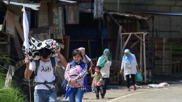 Residents carrying a white flag and their belongings flee to protect themselves from the clash between terrorists and government. At least 24 people have died in the centres since fighting between security forces and Islamist militants erupted.   (AFP) 
