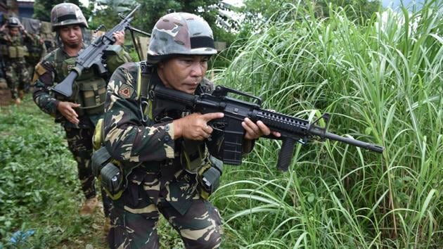 Philippine troops patrol a grassy area near the front-line in Marawi on the southern island of Mindanao  as the armed conflict between government troops and Islamist militants enters its fourth week. The President of Philippines declared martial law in Mindanao to counter the attack, which he said was part of a plan by IS to establish a base in the country.  (AFP) 