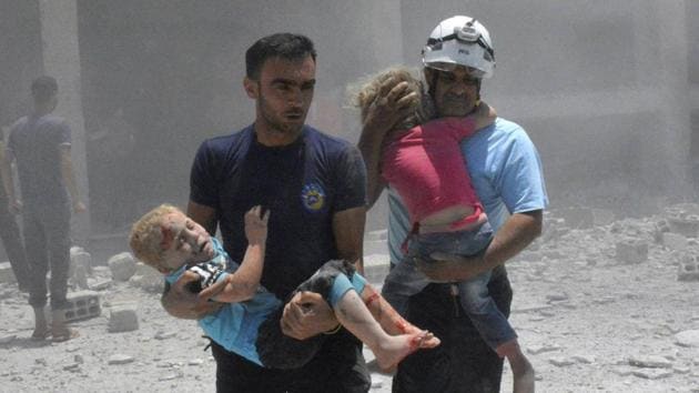 Civil defense workers carry children after airstrikes hit a school housing a number of displaced people in the Daraa province of Syria. (AP)