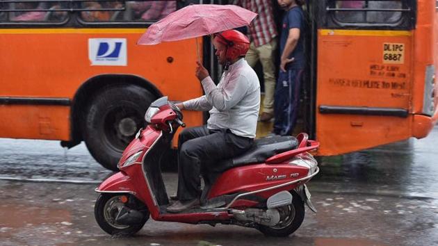 A motorist manoeuvres his morning commute with a skilful display using an umbrella. (Raj K Raj/HT Photo) A motorist manoeuvres his morning commute with a skilful display using an umbrella. (Raj K Raj/HT Photo)