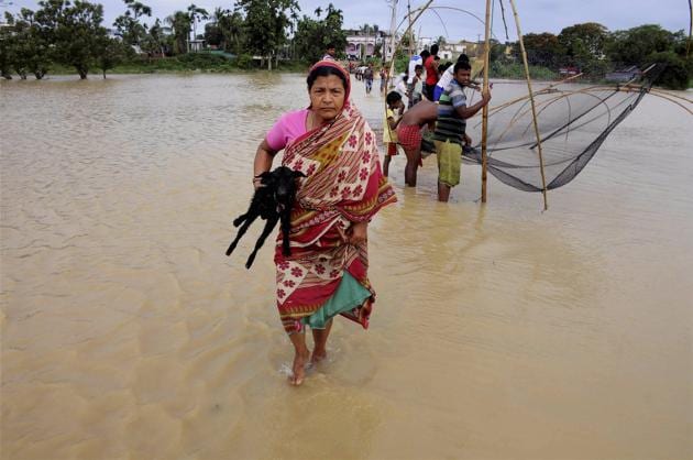 A woman walks to safe place as many others catch fish at the flooded village of Srilanka Basti in Agartala on Tuesday.(PTI)