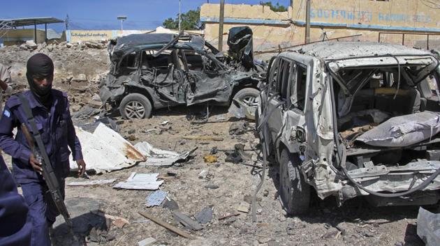 A Somali soldier walks past destroyed vehicles at the scene of a car bomb attack in Mogadishu, Somalia Tuesday, June 20, 2017.(AP Photo)