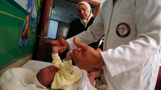 A Syrian doctor examines a newborn at a maternity clinic in the outskirts of the capital Damascus during a childcare awareness campaign by the Syrian American Medical Society. (AFP)