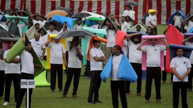 BSF Personnel use yoga mats to protect themselves from rainfall during a group session on International yoga day, in Jammu, Jammu and Kashmir. (Nitin Kanotra/HT Photo) BSF Personnel use yoga mats to protect themselves from rainfall during a group session on International yoga day, in Jammu, Jammu and Kashmir. (Nitin Kanotra/HT Photo)