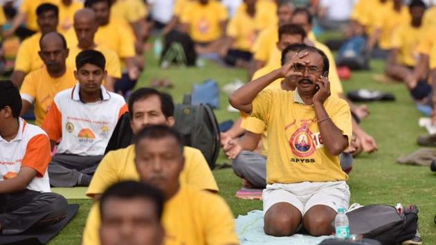 A man speaks on the phone while occupied with a yoga pose on an International Day of Yoga session at Kanteerava Stadium in Bengaluru, Karnataka. (ARIJIT SEN/HT Photo) A man speaks on the phone while occupied with a yoga pose on an International Day of Yoga session at Kanteerava Stadium in Bengaluru, Karnataka. (ARIJIT SEN/HT Photo)