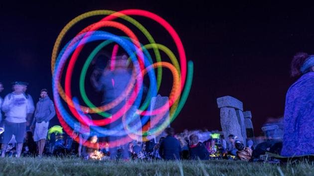 A reveller spins glow sticks as people gather to celebrate the pagan festival of Summer Solstice at Stonehenge in Wiltshire, England. (AFP)