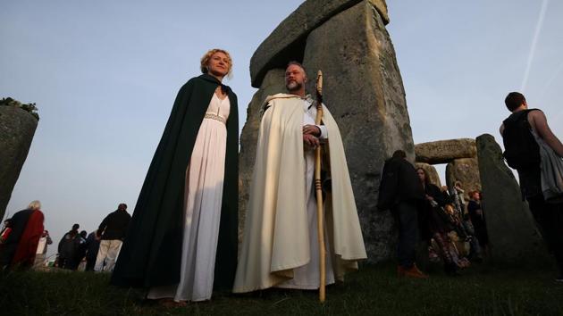 People in druid costume watch the sun rise on the Stonehenge monument. (REUTERS)