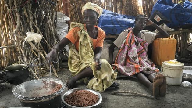 Elizabeth Adwok (L) an ethnic Shilluk who arrived with her seven children in April after having been forcefully displaced from her home three times since South Sudan's conflict began, cooks sorghum in her small hut in the village of Aburoc. (AP) Elizabeth Adwok (L) an ethnic Shilluk who arrived with her seven children in April after having been forcefully displaced from her home three times since South Sudan's conflict began, cooks sorghum in her small hut in the village of Aburoc. (AP)