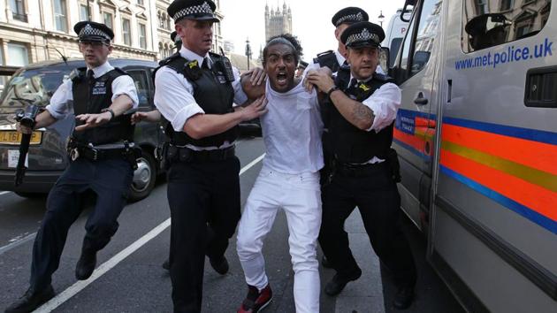 A man is apprehended by police officers as protestors gather in Parliament Square after marching through central London on Wednesday during an anti-government protest to coincide with the State Opening of Parliament and following the deadly fire at Grenfell Tower.(AFP)