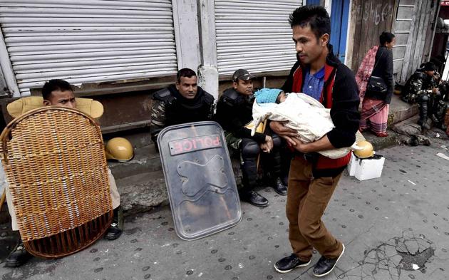 Darjeeling: A man walks past with his new born babby as security personnel guarding in a street during GJM indefinite strike at Chawk Bazar in Darjeeling on Wednesday. PTI Photo by Ashok Bhaumik (PTI6_21_2017_000357B) (PTI) Darjeeling: A man walks past with his new born babby as security personnel guarding in a street during GJM indefinite strike at Chawk Bazar in Darjeeling on Wednesday. PTI Photo by Ashok Bhaumik (PTI6_21_2017_000357B) (PTI)