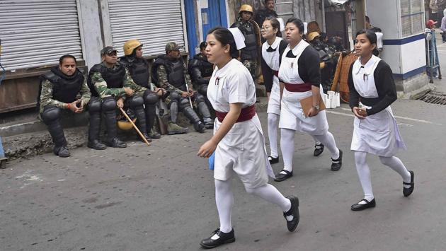 Darjeeling: Nurses walk past security forces personnel guarding in a street during Gorkha Janamukti Morcha's indefinite strike in Darjeeling on Monday. PTI Photo by Ashok Bhaumik (PTI6_19_2017_000131A) (PTI) Darjeeling: Nurses walk past security forces personnel guarding in a street during Gorkha Janamukti Morcha's indefinite strike in Darjeeling on Monday. PTI Photo by Ashok Bhaumik (PTI6_19_2017_000131A) (PTI)
