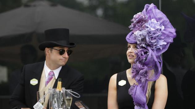 A pretty racegoer poses in a black strappy dress and her giant purple flowers headwear. (AP) A pretty racegoer poses in a black strappy dress and her giant purple flowers headwear. (AP)