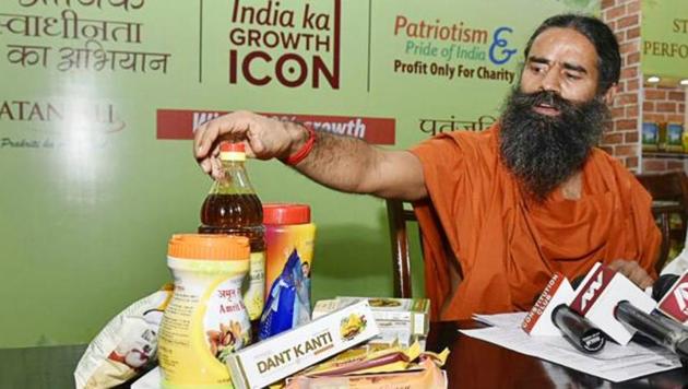 Ramdev shows “Patanjali” products before addressing a press conference in New Delhi.(HT File Photo)