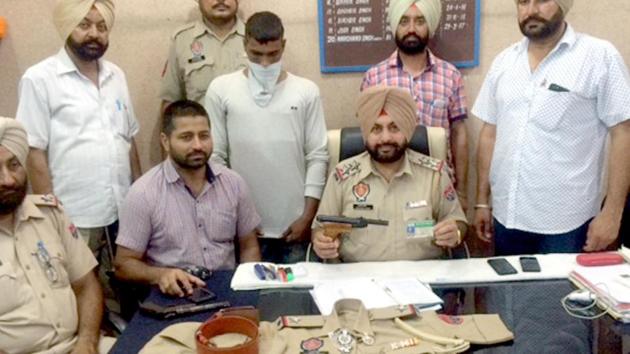Chabhal station house officer (SHO) Harchand Singh (centre) with the imposter  (face covered) ,who was posing as assistant sub-inspector (ASI), at Chabhal in Tarn Taran district on Saturday. (HT Photo)