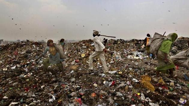 An MCD worker chases away ragpickers with a stick at the Ghazipur landfill site in east Delhi.(Raj K Raj/HT File Photo)