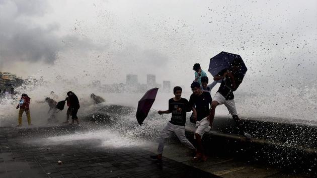 People enjoy a high tide at the Marine Drive promenade following the heavy showers in Mumbai on Sunday. (PTI Photo) People enjoy a high tide at the Marine Drive promenade following the heavy showers in Mumbai on Sunday. (PTI Photo)