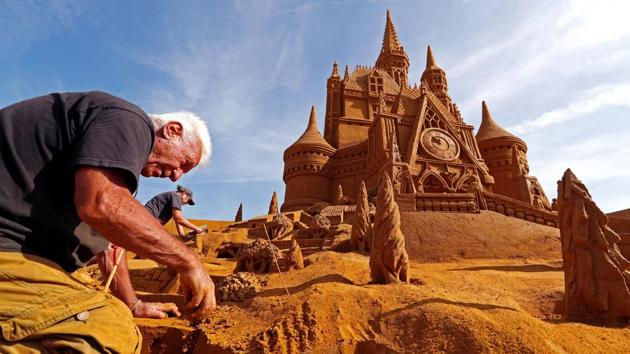 Sand carver Franco Daga from Italy works on a sculpture during the Sand Sculpture Festival "Disney Sand Magic" in Ostend, Belgium on June 22, 2017. (Yves Herman/REUTERS)