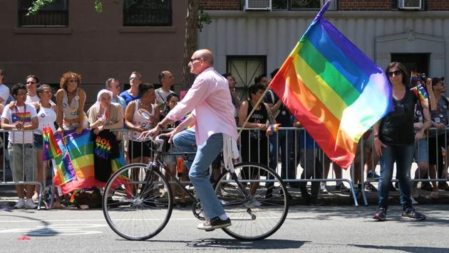 Man on a bicycle at the Gay Pride Parade on 5th ave, New York. The rainbow colours are the symbol of lesbian, gay, bisexual and transgender pride and diversity.(Shutterstock)