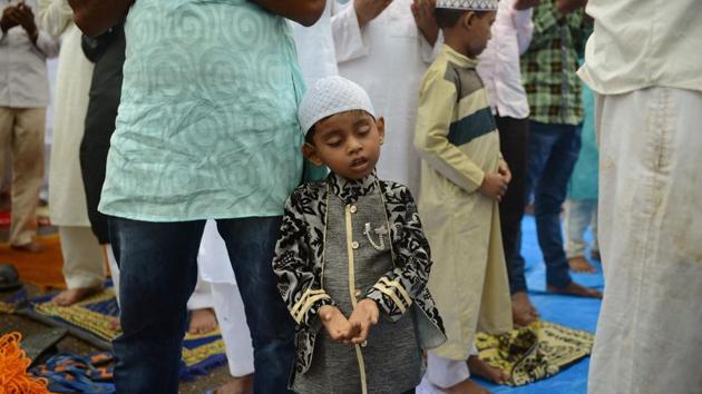 A boy rests on his father as he attends the morning prayers outside the Bandra railway station in Mumbai. (Punit PARANJPE / AFP)