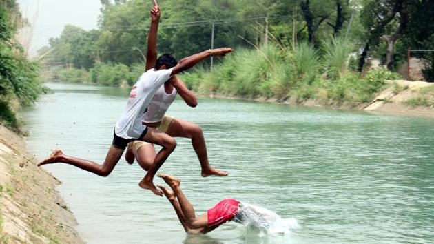 Children dive into a canal to beat the heat in Talwandi Sabo at Bathinda on Tuesday. (Sanjeev Kumar/HT Photo)
