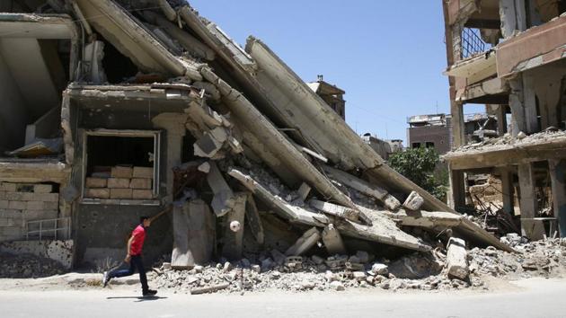 A boy plays with a ball in front of damaged buildings during Eid al-Fitr celebration in the rebel-held besieged Douma neighbourhood of Damascus, Syria. (REUTERS) A boy plays with a ball in front of damaged buildings during Eid al-Fitr celebration in the rebel-held besieged Douma neighbourhood of Damascus, Syria. (REUTERS)