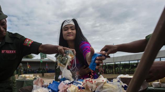 An ethnic Wa woman from UWSA (United Wa State Army) empties a packet of Ya Ba drug before they are set on fire during a drug burning ceremony. (AFP) An ethnic Wa woman from UWSA (United Wa State Army) empties a packet of Ya Ba drug before they are set on fire during a drug burning ceremony. (AFP)