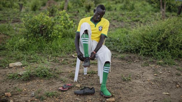A South Sudanese refugee soccer player laces his boots as he prepares for a match. (Ben Curtis / AP) 