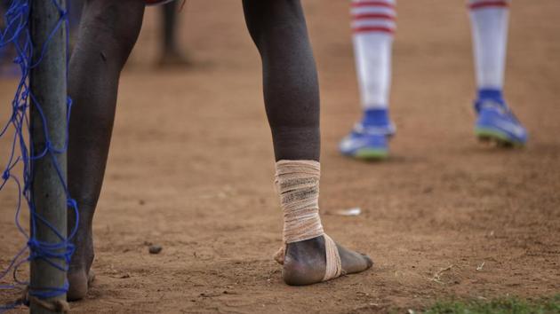 A refugee soccer player plays barefoot and bandaged during a match in the Bidi Bidi refugee settlement. (Ben Curtis / AP) 
