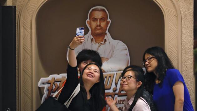 Women take a selfie with a poster of Bollywood blockbuster Dangal on display at a cinema in Beijing(AP)