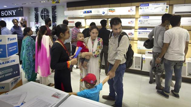 A family shops for a washing machine in New Delhi as others look at electronic items ahead of the implementation of the GST on Friday. (AP) A family shops for a washing machine in New Delhi as others look at electronic items ahead of the implementation of the GST on Friday. (AP)