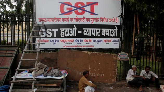 Labourers sit next to a banner after a protest against the implementation of the goods and services tax (GST) on textiles, in the old quarters of Delhi.(REUTERS)