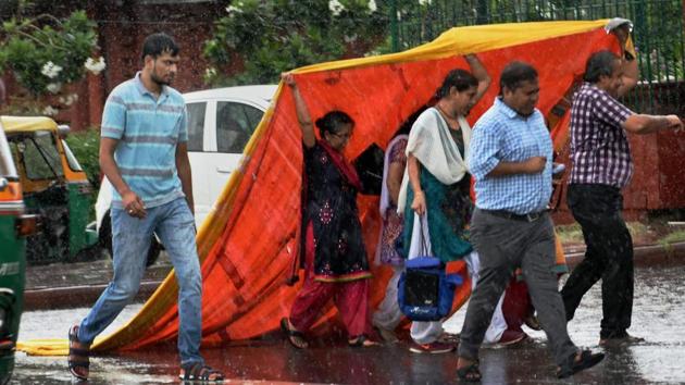 People cover themselves with a plastic sheet during rains near Rail Bhavan. (Subhav Shukla / PTI) People cover themselves with a plastic sheet during rains near Rail Bhavan. (Subhav Shukla / PTI)