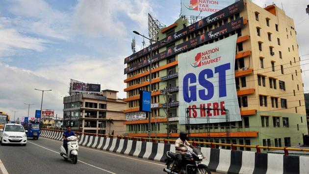 People go past a GST poster on the wall of a building, in Guwahati. (PTI Photo) People go past a GST poster on the wall of a building, in Guwahati. (PTI Photo)
