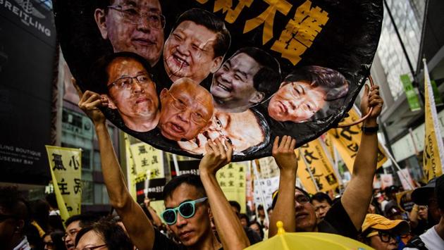 A protester holds a wok-shaped artwork with pictures showing the faces of (top row L-R) Chairman of the Standing Committee of the National People's Congress of China Zhang Dejiang, Chinese President Xi Jinping, former chief executive of Hong Kong Leung Chun-ying, new Chief Executive of Hong Kong Carrie Lam during a during a protest march in Hong Kong coinciding with the 20th anniversary of the city's handover from British to Chinese rule. (Anthony Wallace / AFP) A protester holds a wok-shaped artwork with pictures showing the faces of (top row L-R) Chairman of the Standing Committee of the National People's Congress of China Zhang Dejiang, Chinese President Xi Jinping, former chief executive of Hong Kong Leung Chun-ying, new Chief Executive of Hong Kong Carrie Lam during a during a protest march in Hong Kong coinciding with the 20th anniversary of the city's handover from British to Chinese rule. (Anthony Wallace / AFP)