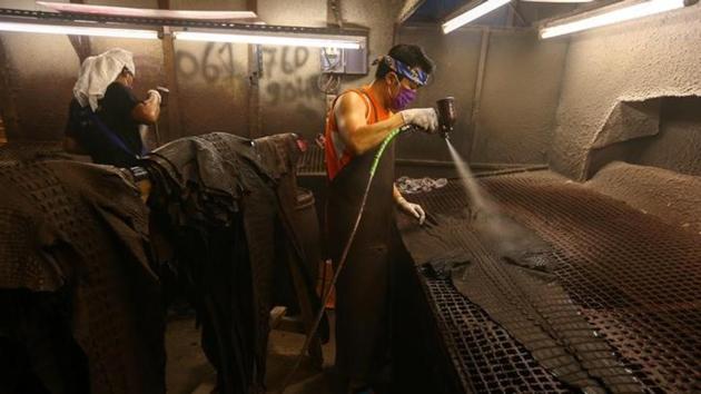 Workers spray coating colour on dyed crocodile skins at a crocodile leather tannery. 
