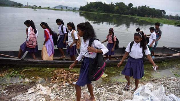 School girls cross a flooded area by a boat at Rajbari village on the ourskirts of Guwahati. (PTI)