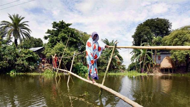 A woman walks on a makeshift bamboo bridge to cross a flooded area at Morigaon district, in Assam. (PTI Photo) A woman walks on a makeshift bamboo bridge to cross a flooded area at Morigaon district, in Assam. (PTI Photo)