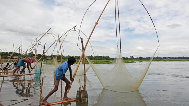 Men pull their fishing nets out from a flooded paddy field after heavy rains in Morigaon district . (Anuwar Hazarika / Reuters)