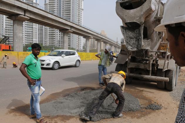 Construction workers mend the potholed stretch of Golf Course Road on Wednesday. (Parveen kumar/HT PHOTO) Construction workers mend the potholed stretch of Golf Course Road on Wednesday. (Parveen kumar/HT PHOTO)