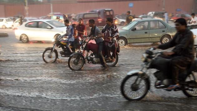 Pakistani commuters travel on a street during a heavy rain shower in Karachi.(AFP File Photo)
