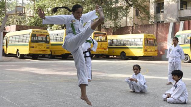 A taekwondo instructor demonstrates a move as children look on near Mandir Marg in Delhi.  (Sonu Mehta/HT PHOTO) 