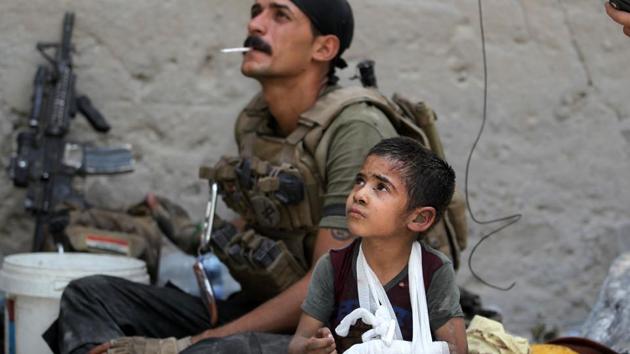 Omar, a young wounded Iraqi boy whose family was killed in the ongoing battles to oust the Islamic State (IS) group from Mosul, sits with members of the Counter Terrorism Services (CTS) as they help him to flee the Old City of Mosul. (AFP)