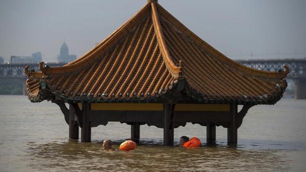 People swim past a pagoda in a flooded riverside park in Wuhan in central China's Hubei Province. (AP) People swim past a pagoda in a flooded riverside park in Wuhan in central China's Hubei Province. (AP)