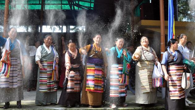 Tibetans sprinkle chappa (cooked wheat powder) during the special morning-prayer session on the occasion 82nd birthday of Dalai Lama at a monastery in Mcleodganj, near Dharamsala on Thursday. (Shyam Sharma/HT Photo) 