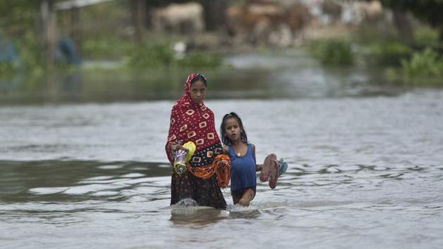 A woman and a child cross a waterlogged street at Burgaon, 80 kilometers (50 miles) east of Gauhati. Northeast’s biggest city, Guwahati, also came under threat as the water level of the swelling Brahmaputra river crossed the danger level mark on Wednesday afternoo (Anupam Nath / AP)