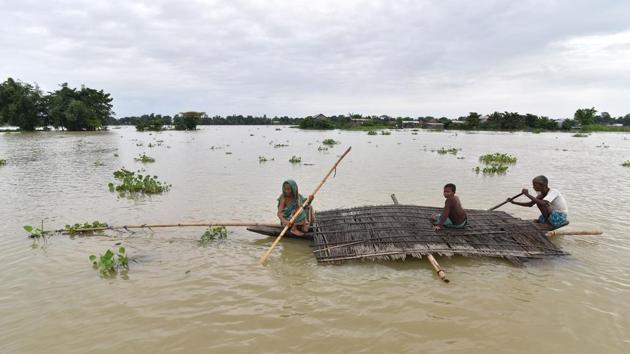Villagers carry the dismantled roof of their house through floodwaters in Balimukh Ashigarh villag. (Biju BORO / AFP)