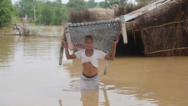 A man lifts a cot as he wades through flood waters to shift to a safer place after his house got partially submerged following heavy rains at a village in Vindhyachal in Mirzapur. (PTI) A man lifts a cot as he wades through flood waters to shift to a safer place after his house got partially submerged following heavy rains at a village in Vindhyachal in Mirzapur. (PTI)