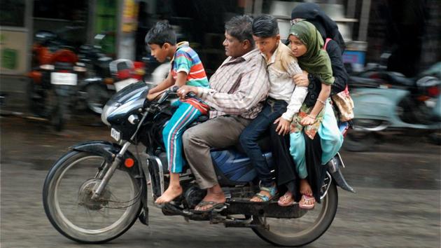 A couple with their three children riding on motorcycle in rains in Hyderabad. (PTI) A couple with their three children riding on motorcycle in rains in Hyderabad. (PTI)