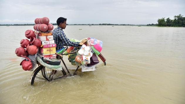 A vendor pushes a bicycle carrying his wares through floodwaters in Balimukh Ashigarh village in Morigoan district. (Biju BORO / AFP)